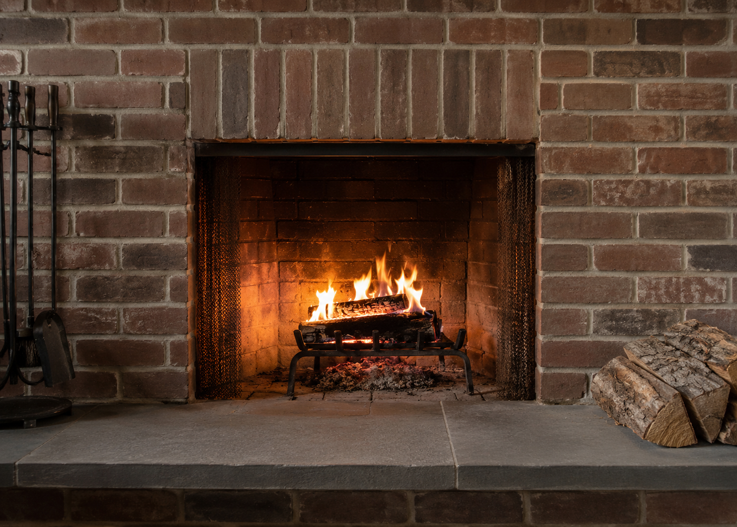 Traditional brick masonry fireplace with a lit fire.